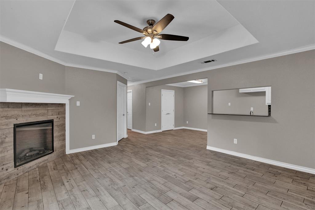 a view of an empty room with wooden floor and a fireplace