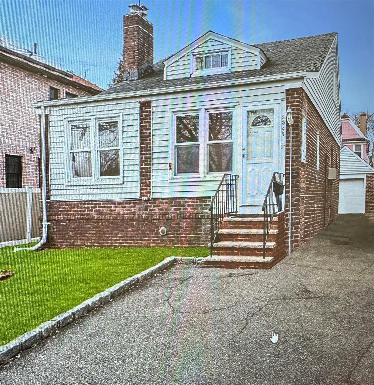 View of front of home with a front yard, an outbuilding, and a garage