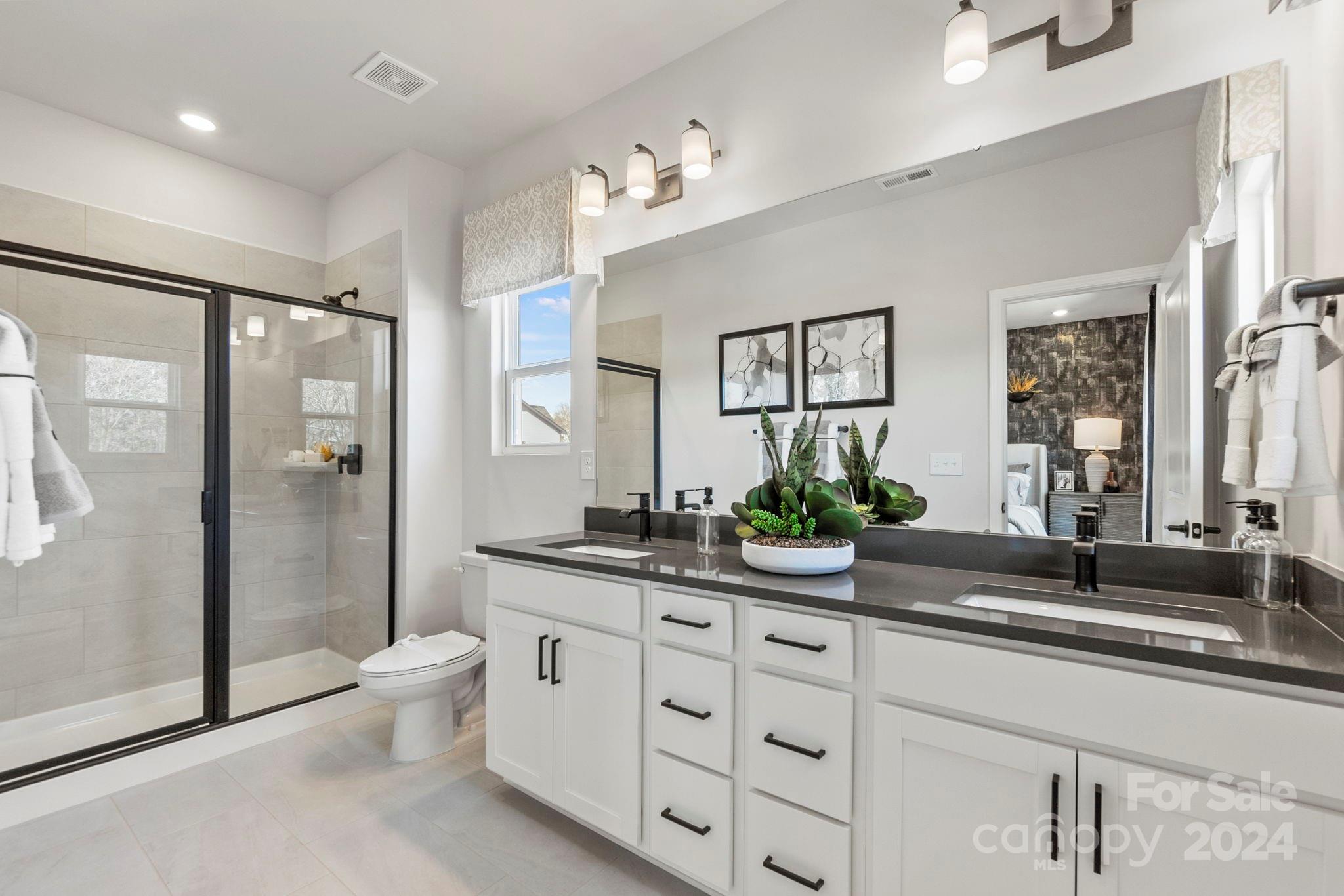 a spacious bathroom with a double vanity sink a large mirror a bathtub and shower