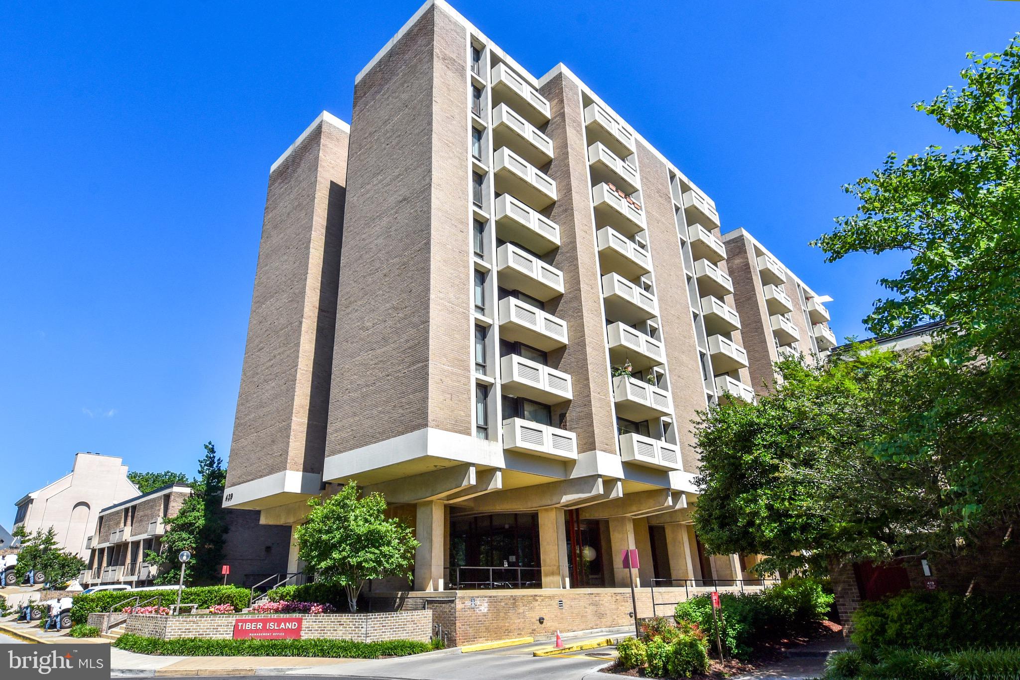 a front view of multi story residential apartment building with yard and parking space