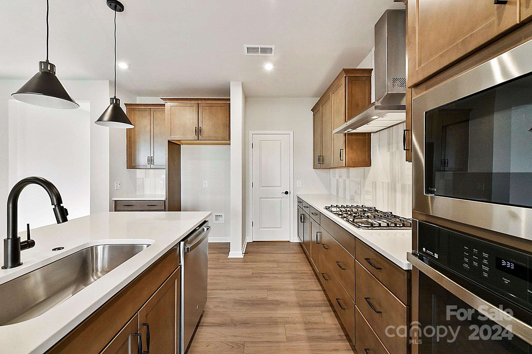 a kitchen with stainless steel appliances granite countertop a sink a stove and a refrigerator