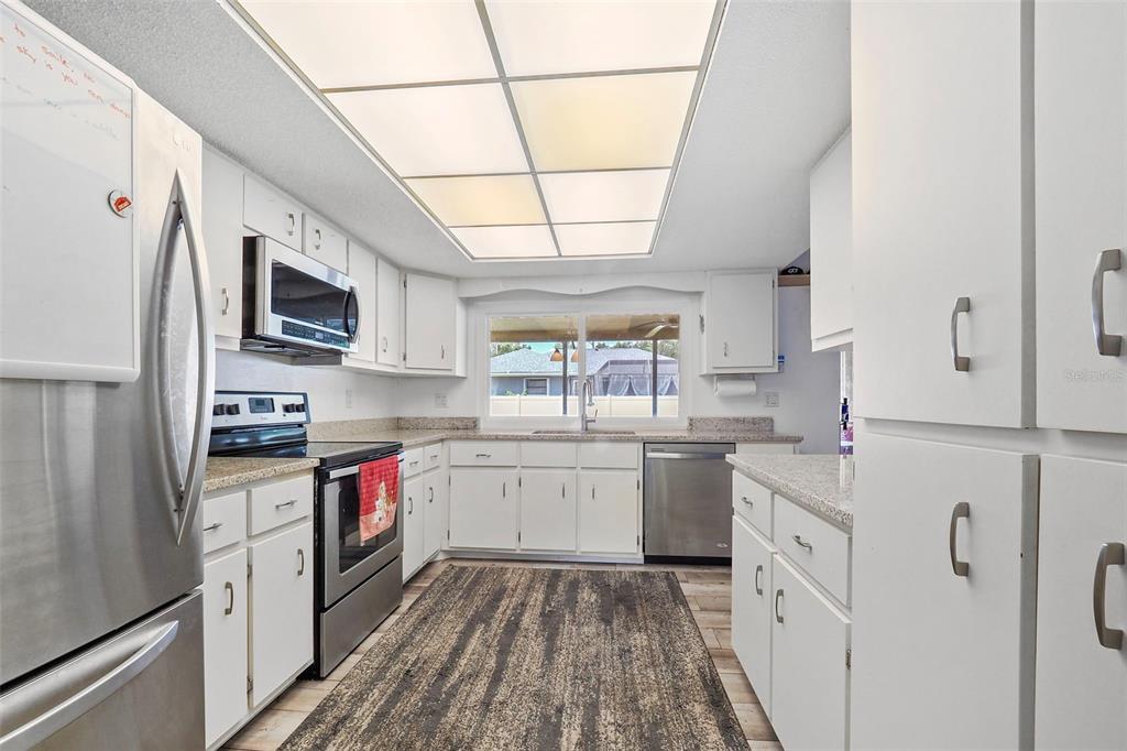 a kitchen with granite countertop appliances a sink and a refrigerator