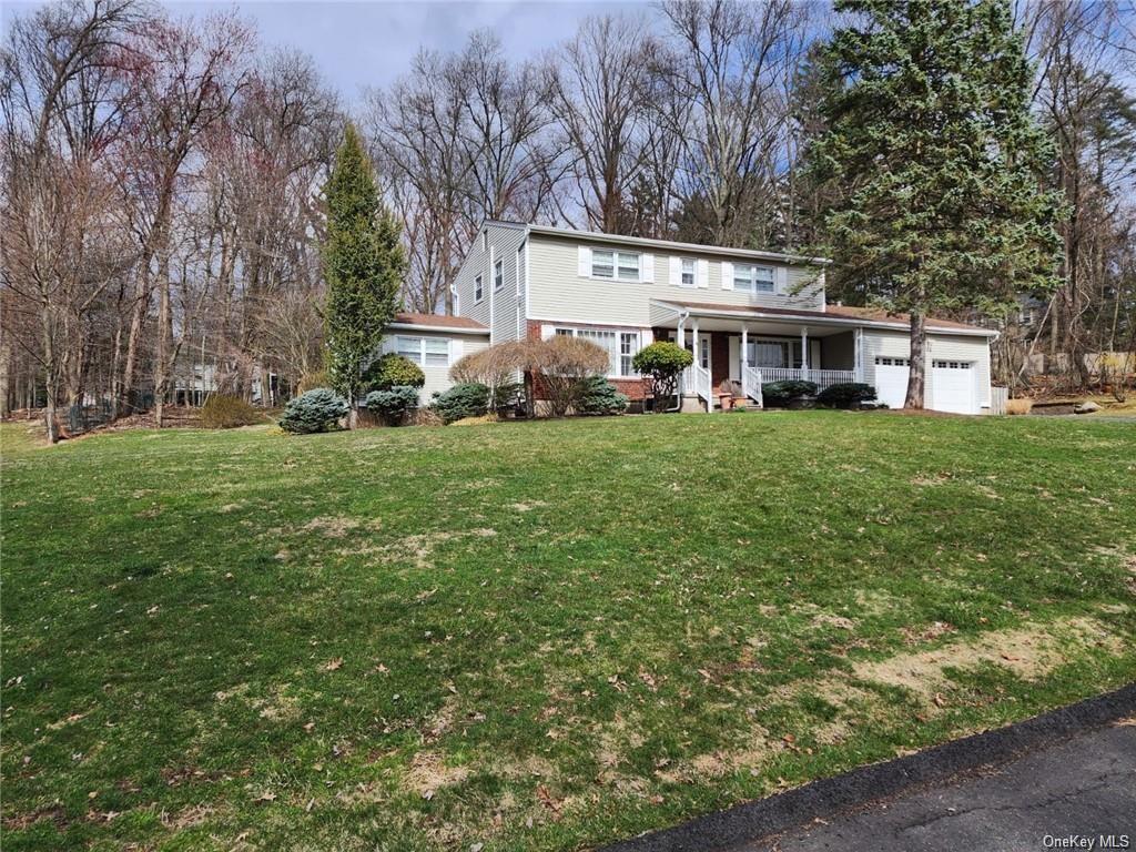 View of property with a front lawn, a garage, and a porch