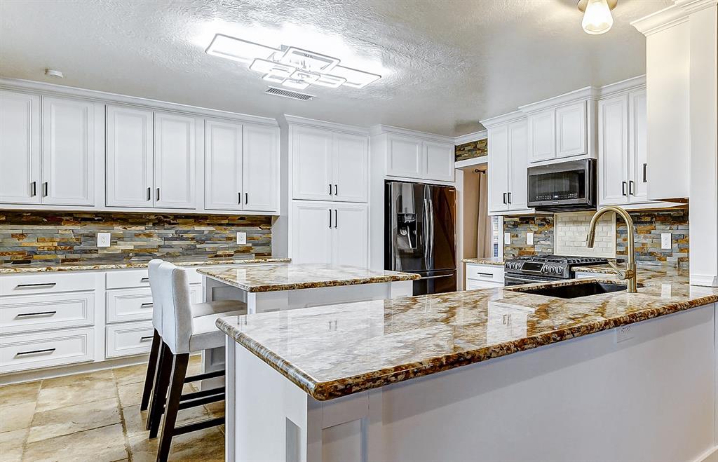 a kitchen with granite countertop stainless steel appliances and white cabinets