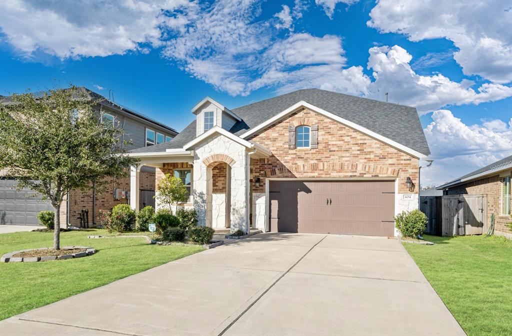 The home welcomes you with a wide driveway and a beautifully manicured front lawn, creating a warm and inviting first impression.