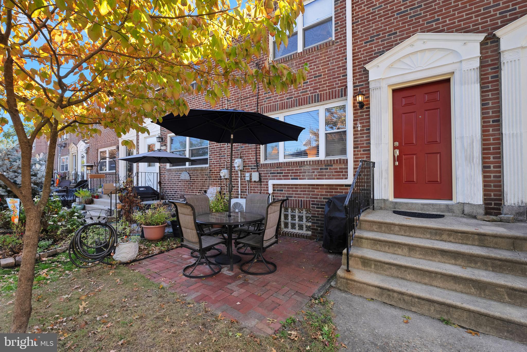 a view of a patio with table and chairs under an umbrella with barbeque grill and wooden fence