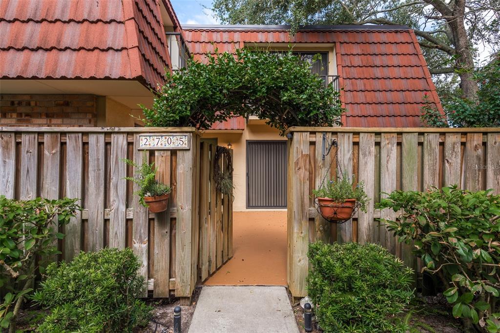 a backyard of a house with potted plants and wooden fence