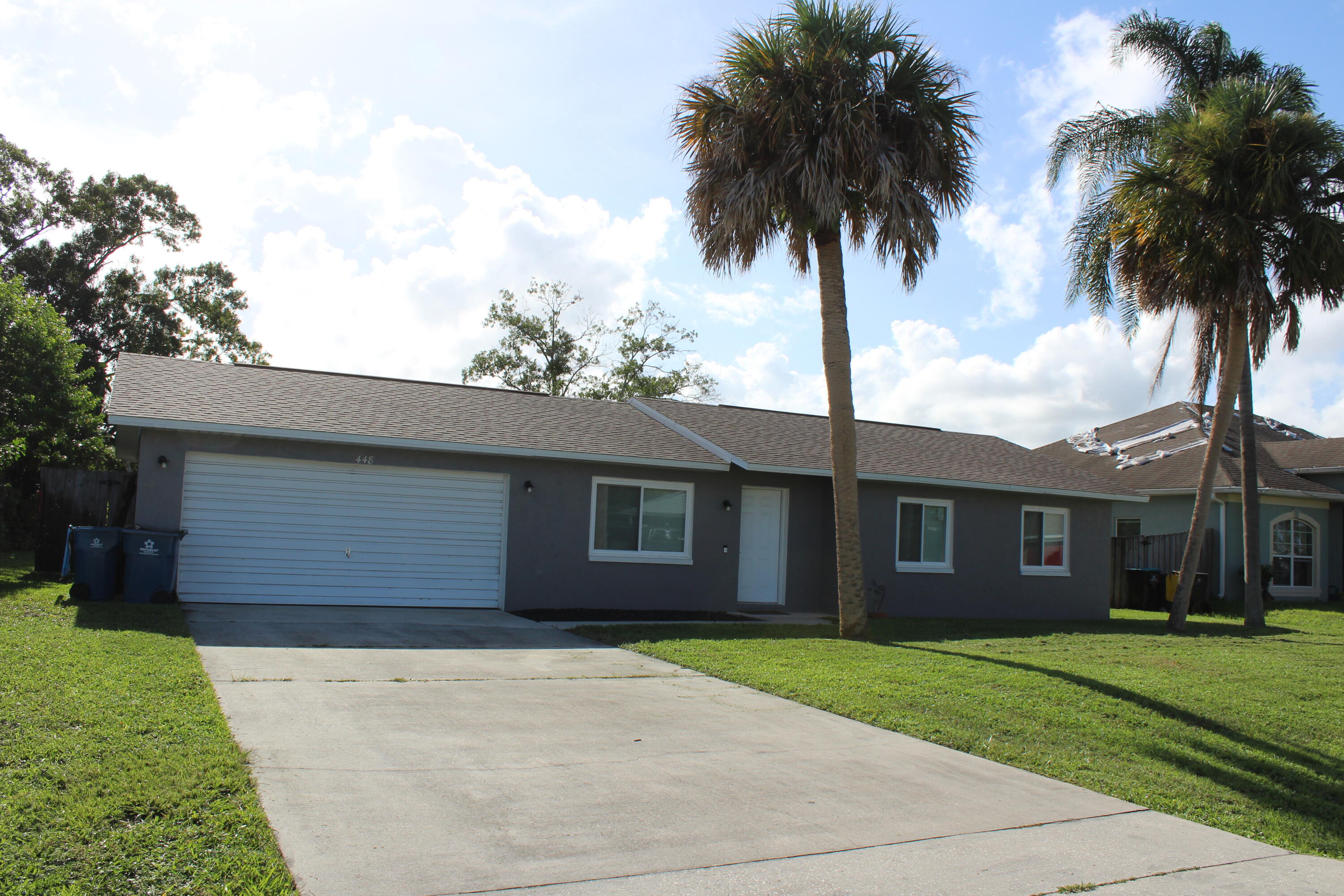 front view of a house with a yard and palm trees