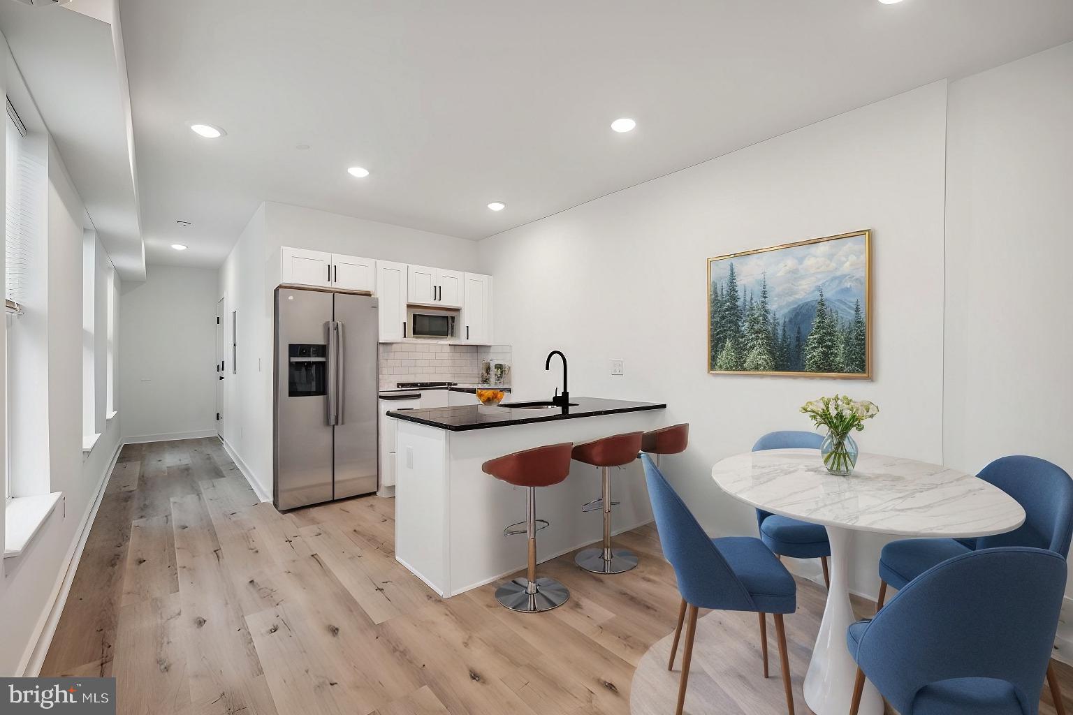 a kitchen with stainless steel appliances a dining table chairs and wooden floor