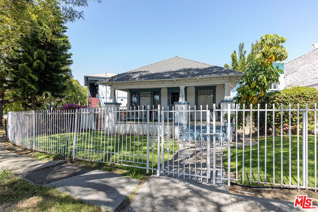 a view of a house with a small yard plants and large trees