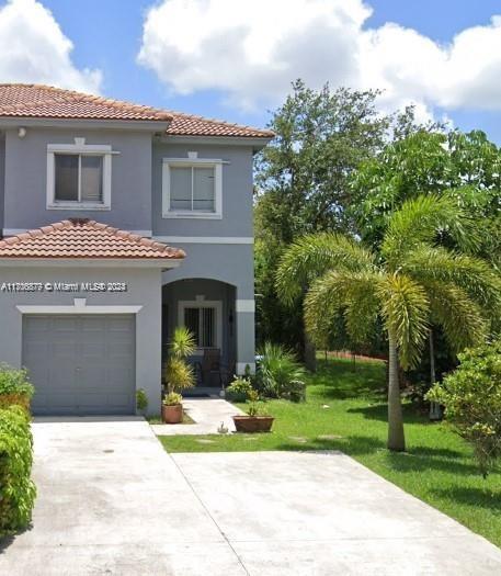 a front view of a house with a garden and trees