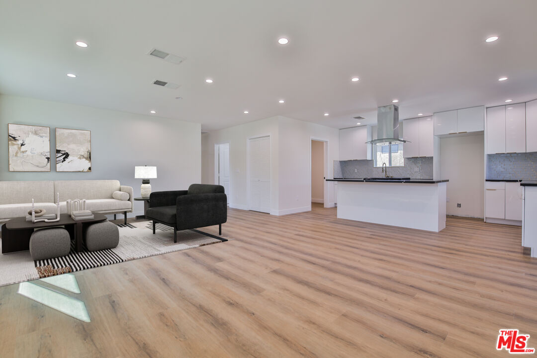 a large room with kitchen island white cabinets and wooden floor