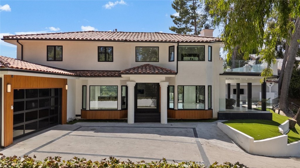 a front view of a house with a lots of windows and plants