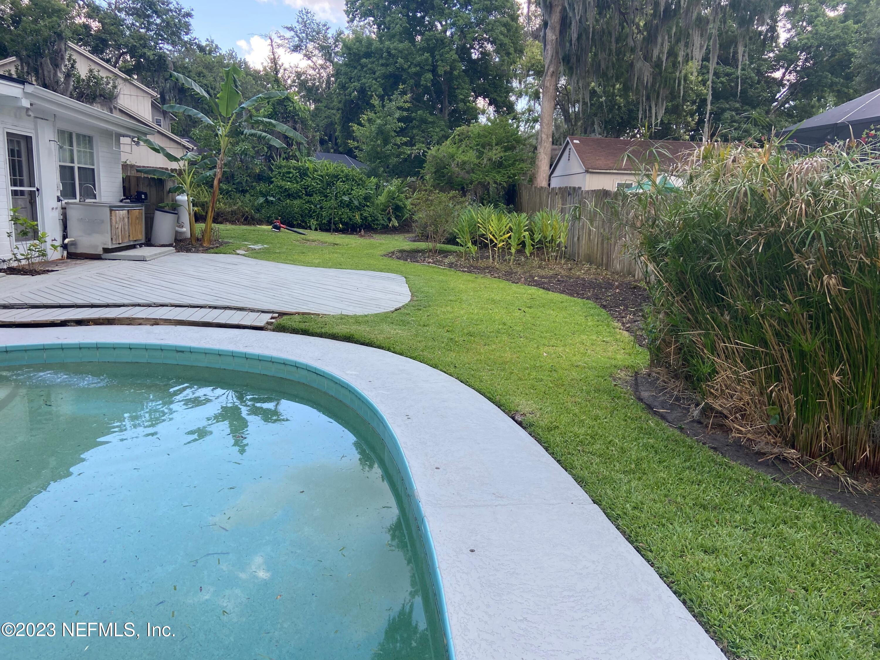 a view of a swimming pool with a yard and plants