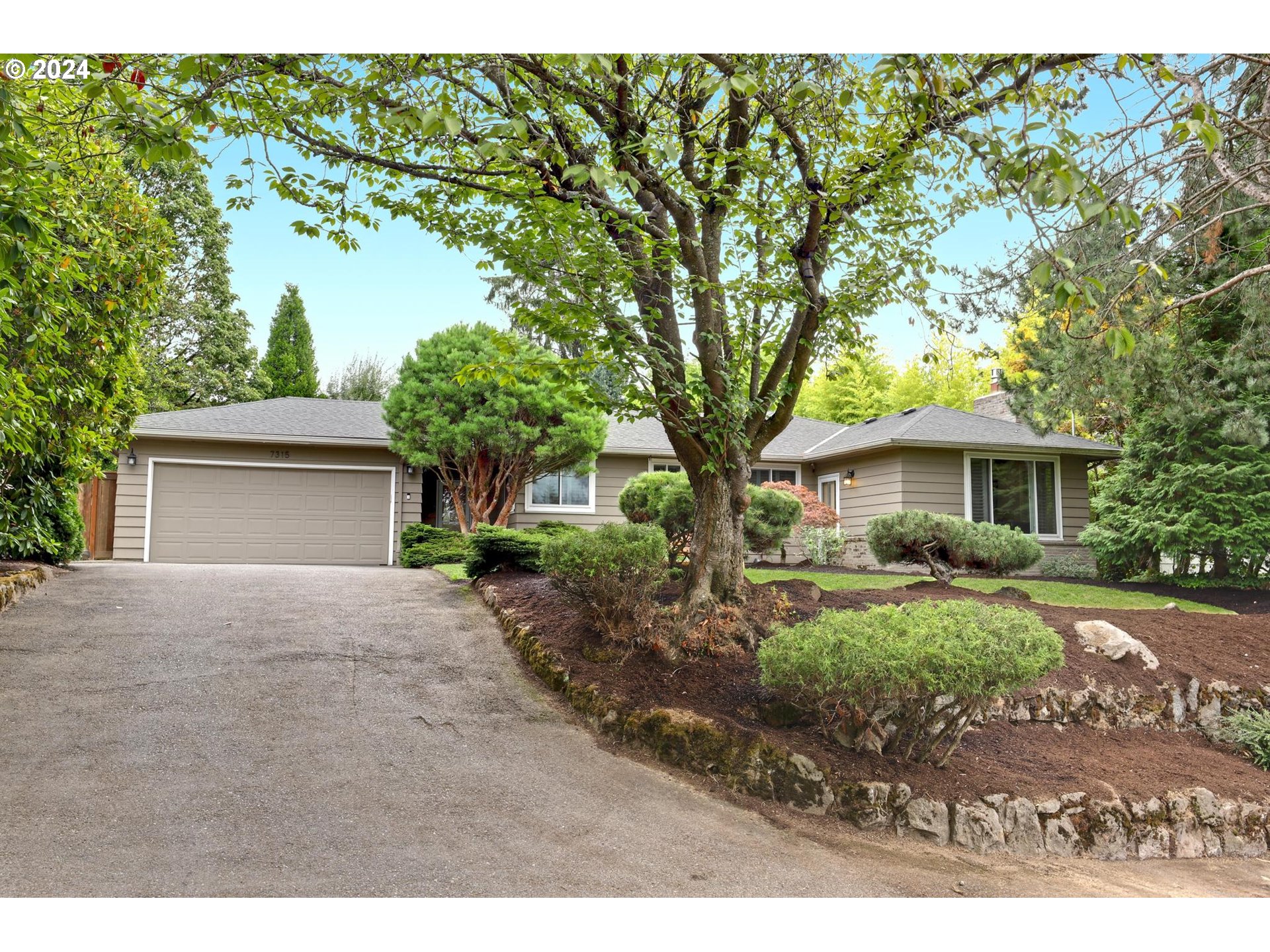 a front view of a house with a garden and trees