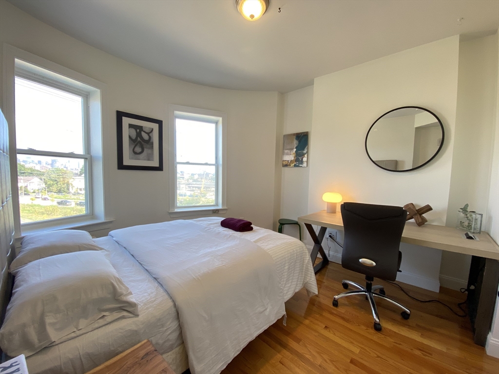 a bedroom with a chair and a window