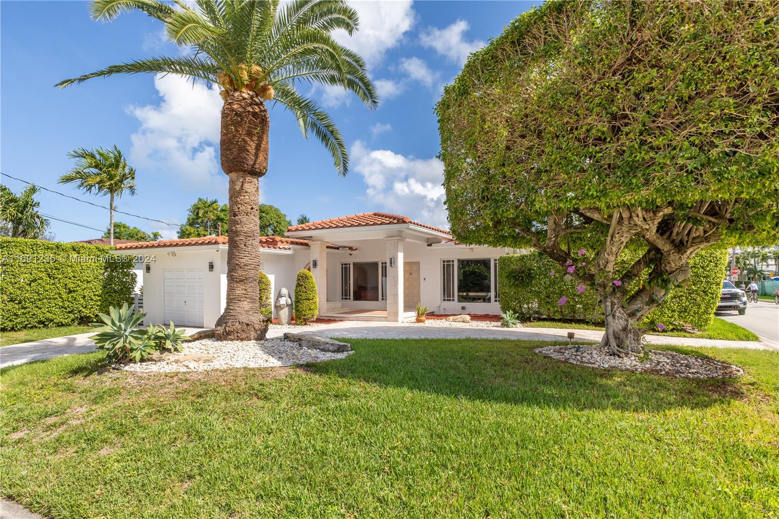 a front view of a house with a garden and tree