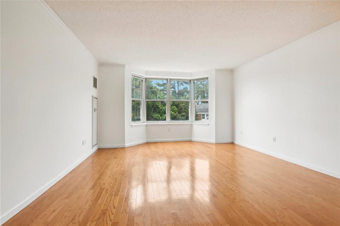 Empty room with light hardwood / wood-style floors and a textured ceiling