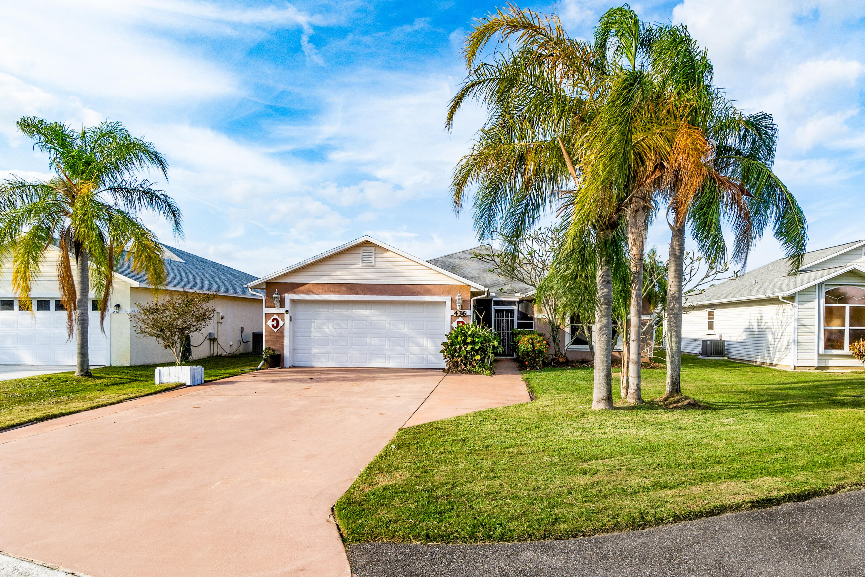 a front view of a house with a yard and palm trees