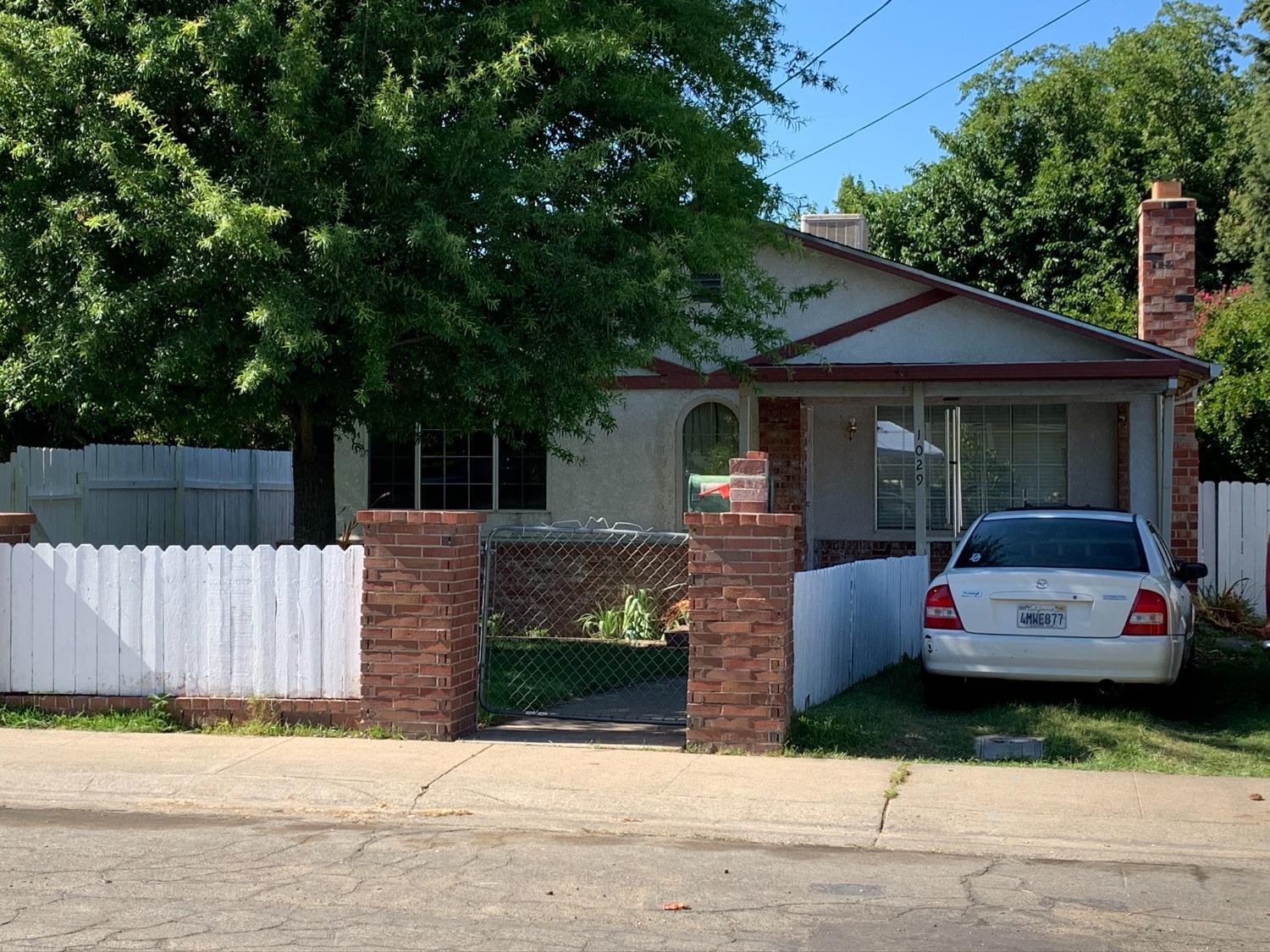 a front view of a house with a garden and tree