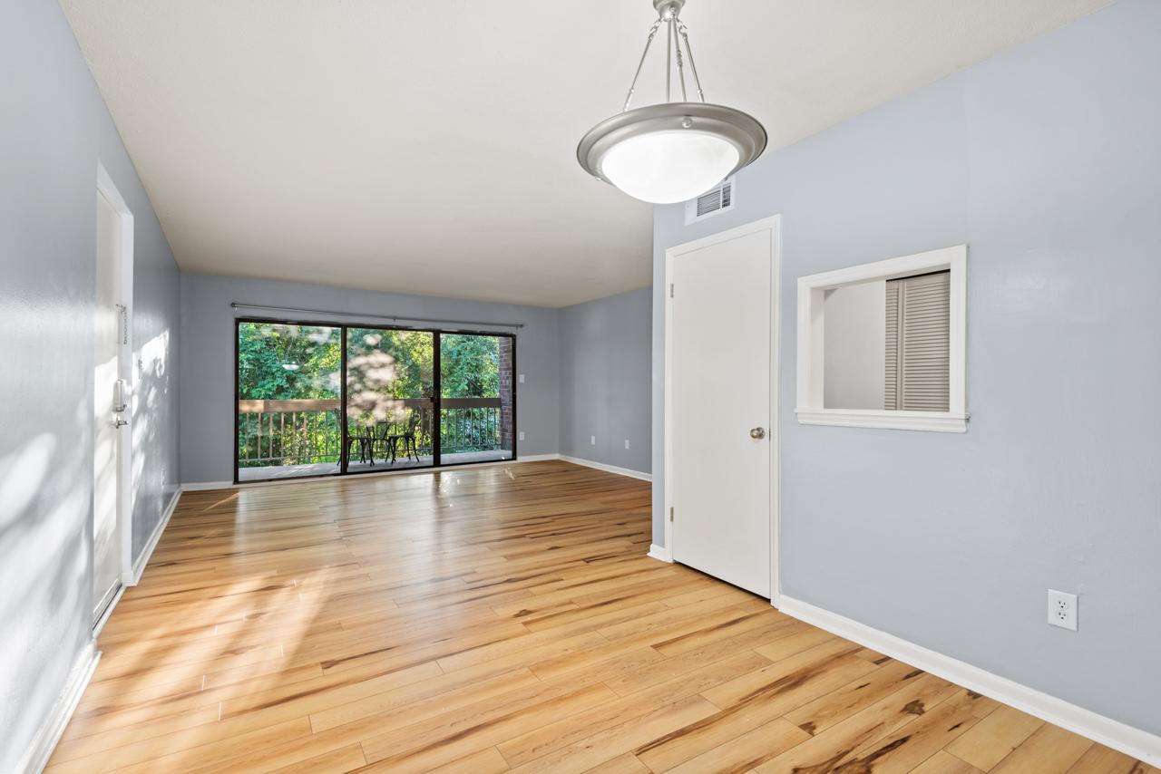 a view of an empty room with wooden floor and a window