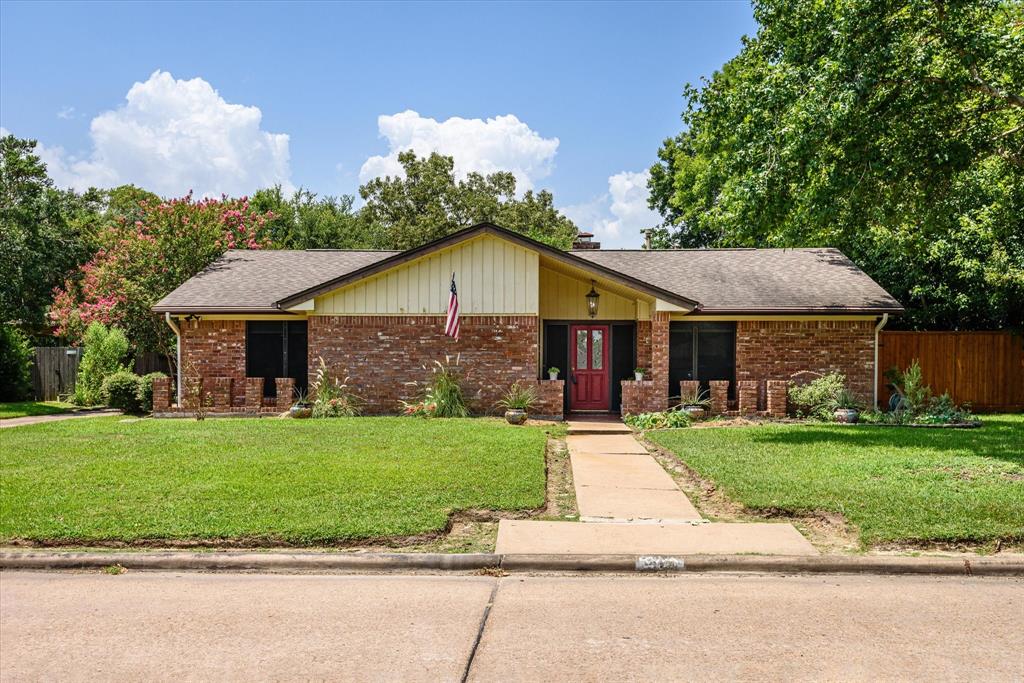 A charming single-story 4/2 brick home featuring a well-manicured lawn, and a detached two-car garage, set in a pleasant neighborhood with mature trees.