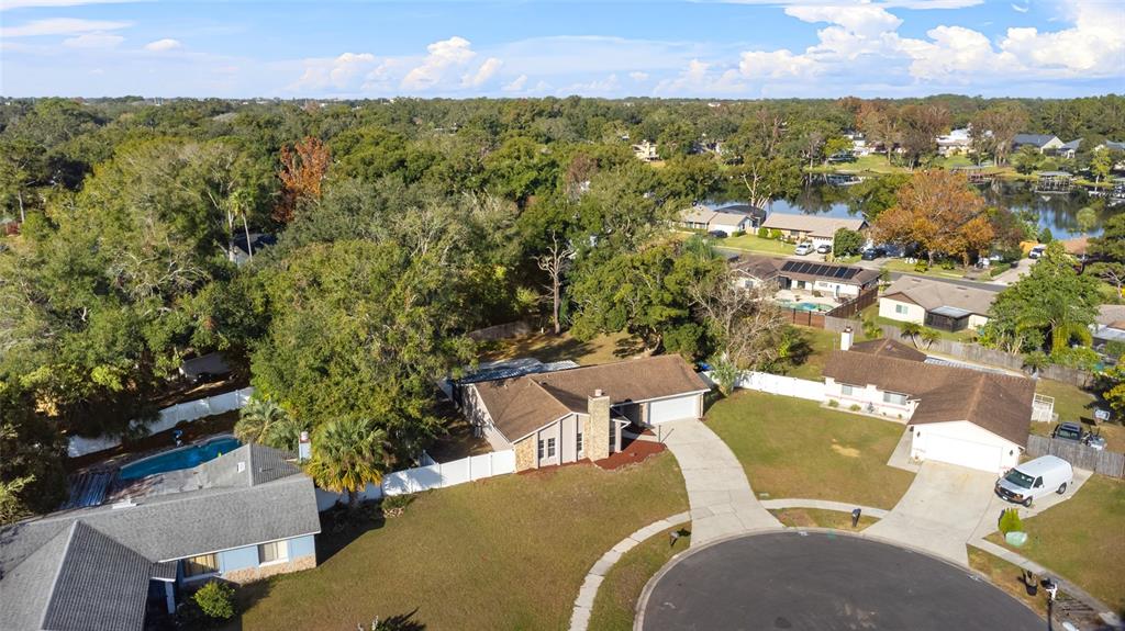 an aerial view of a residential houses with outdoor space and trees all around