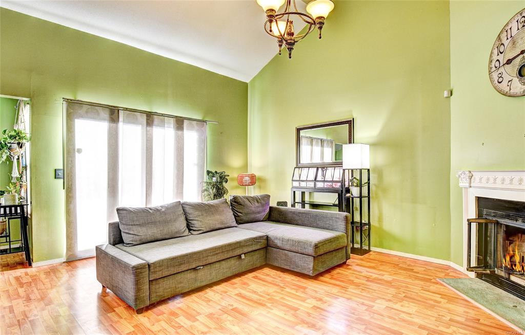 Living room featuring high vaulted ceiling, light hardwood / wood-style floors, an inviting chandelier, and a healthy amount of sunlight