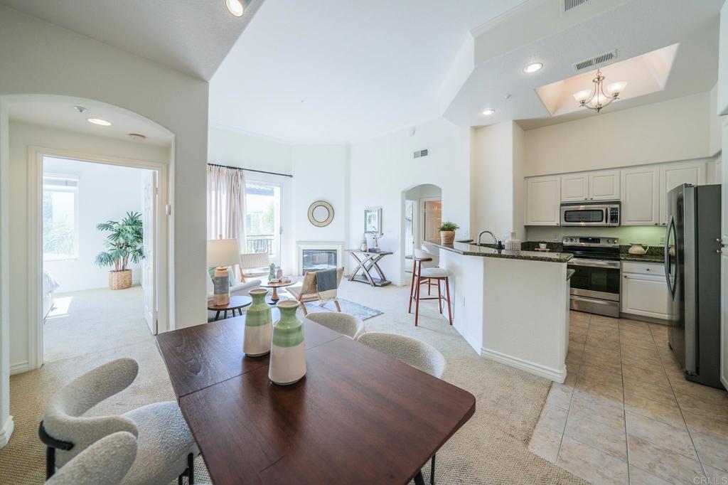 a kitchen with stainless steel appliances kitchen island granite countertop a refrigerator a stove a sink dishwasher and white cabinets with wooden floor