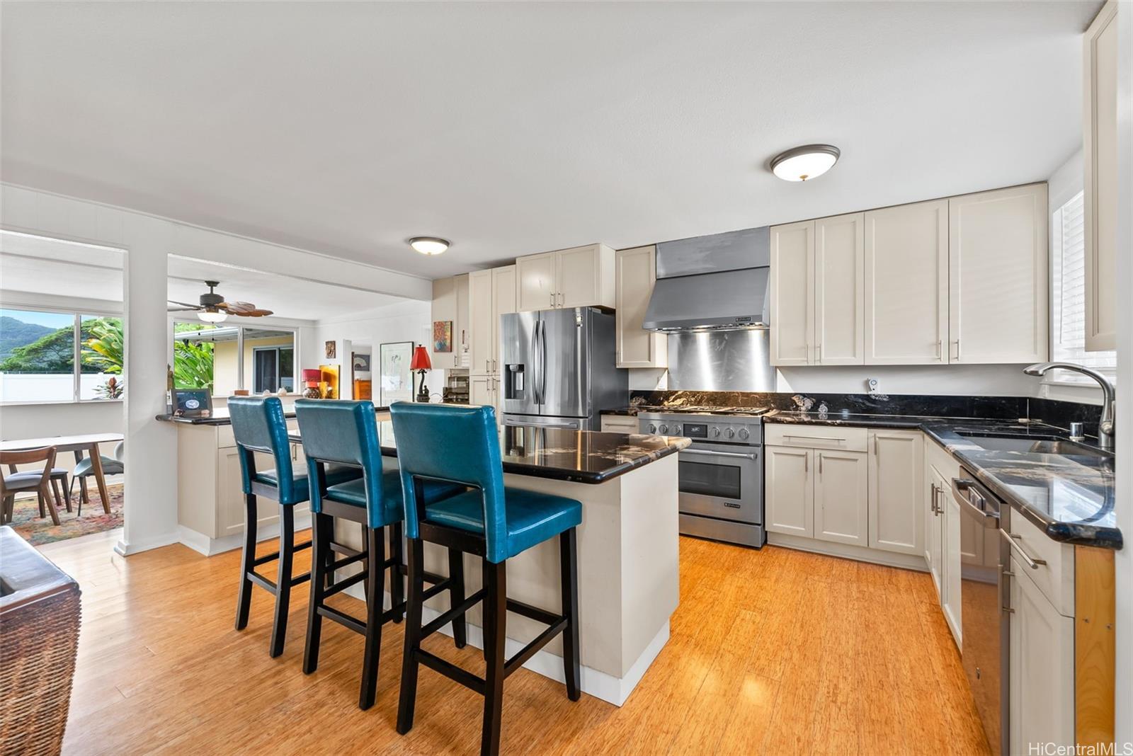 a kitchen with stainless steel appliances kitchen island granite countertop a table chairs microwave and sink