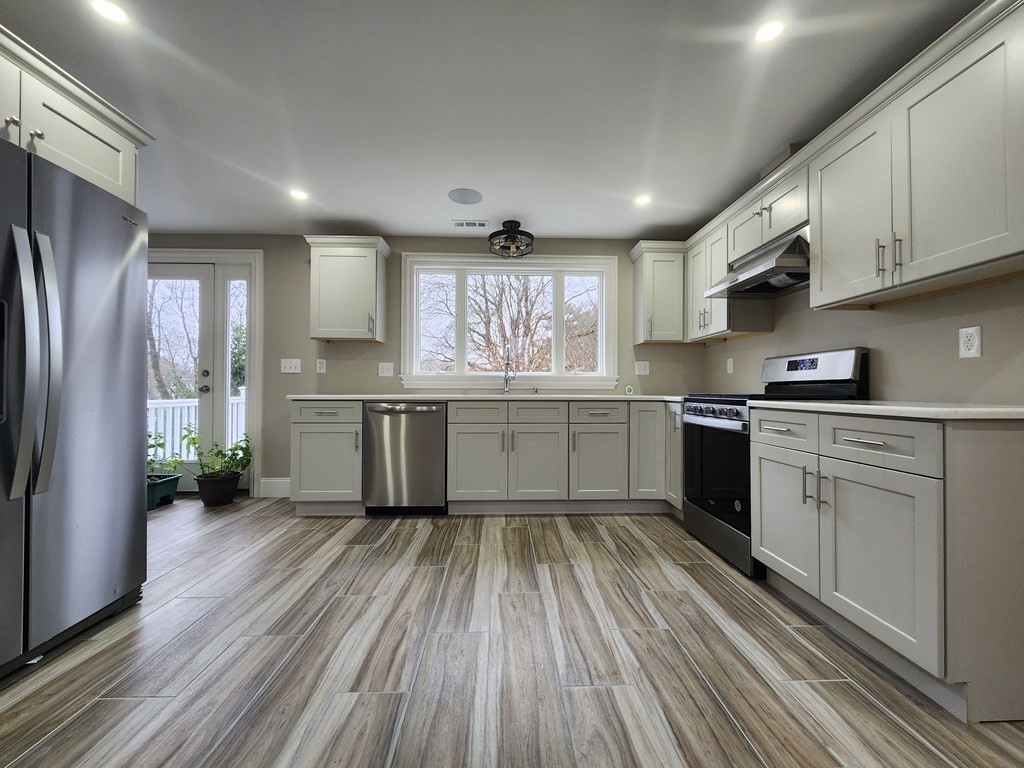 a kitchen with cabinets wooden floor and stainless steel appliances