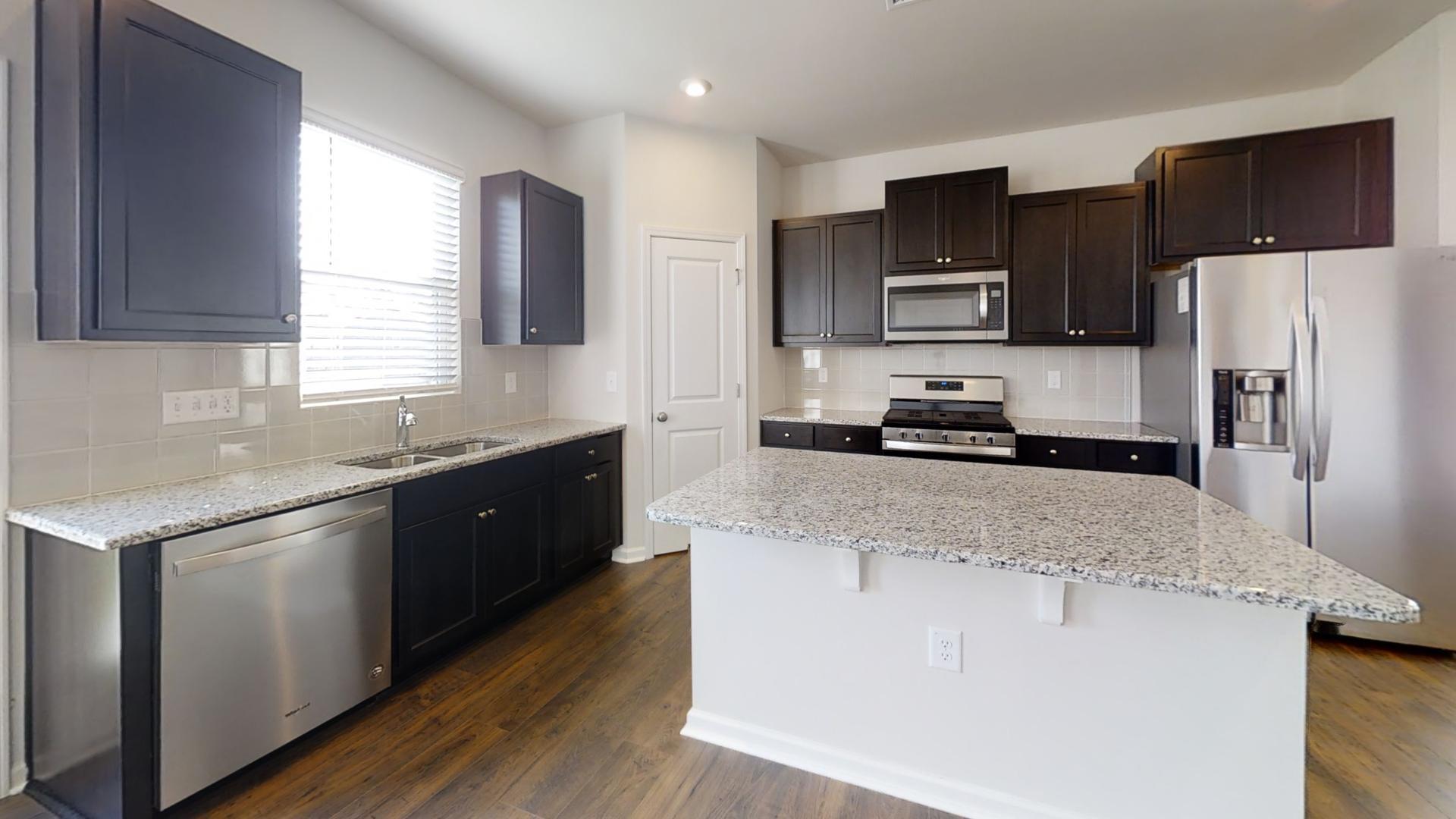 a kitchen with granite countertop a refrigerator stove top oven and sink