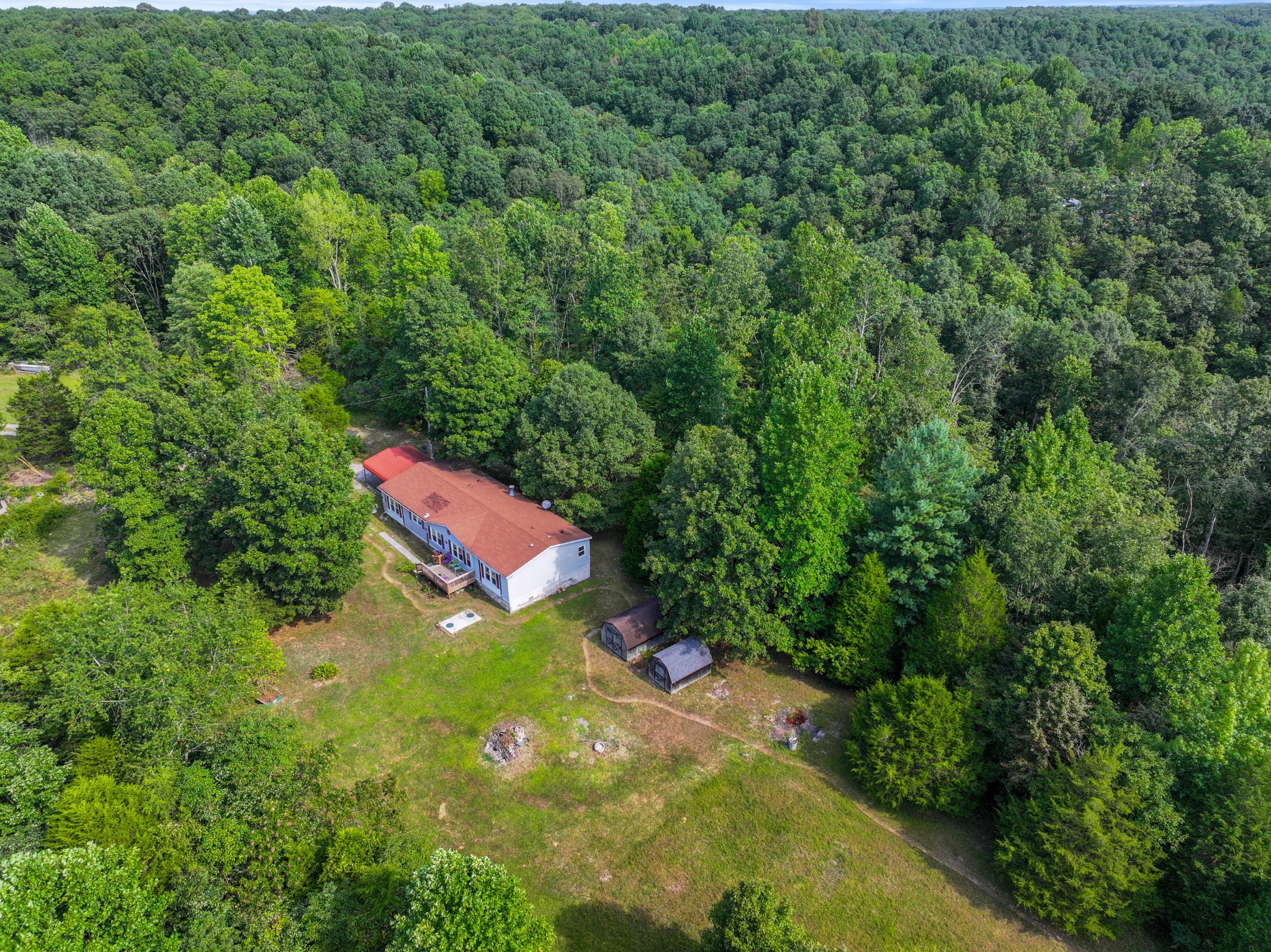 an aerial view of residential house with outdoor space and trees all around