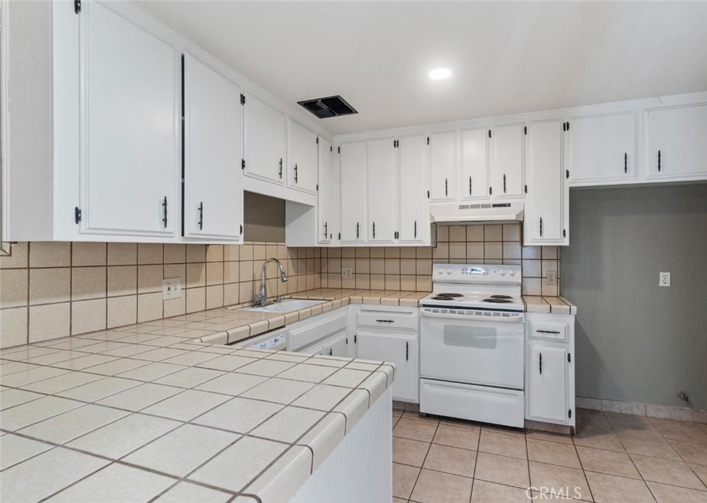 a kitchen with granite countertop white cabinets and white appliances