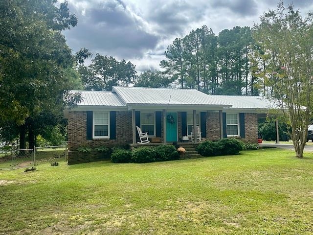 Ranch-style house with a front yard and covered porch