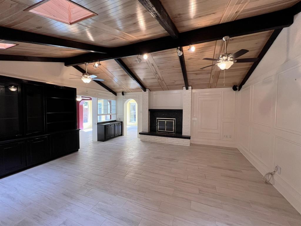 a view of empty room with wooden floor and kitchen