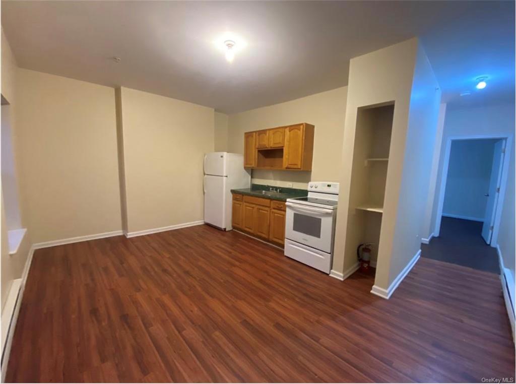 Kitchen featuring sink, dark wood-type flooring, and white appliances