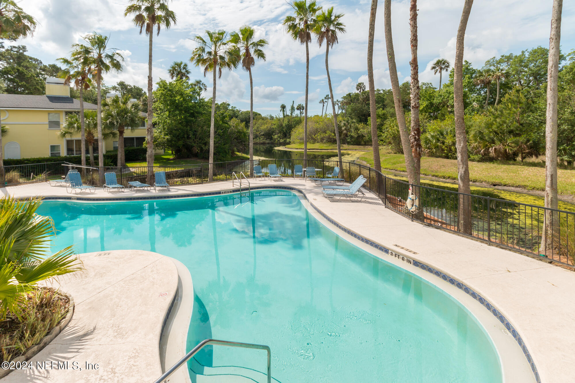 a view of a swimming pool with a yard and palm trees