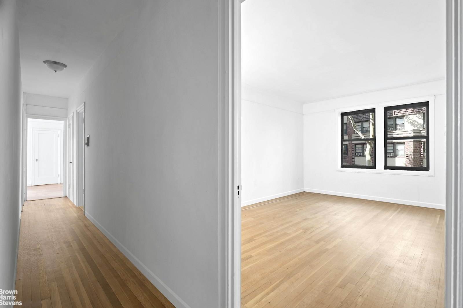 a view of an empty room with window and wooden floor