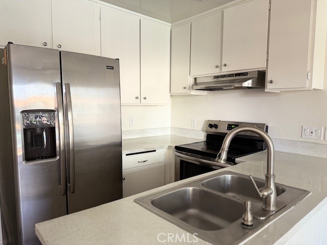 a kitchen with stainless steel appliances granite countertop a refrigerator a sink a stove and white cabinets