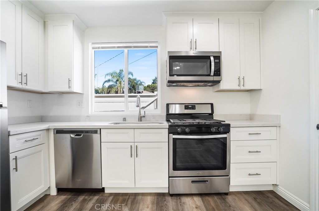 a kitchen with stainless steel appliances a stove a microwave a sink and cabinets