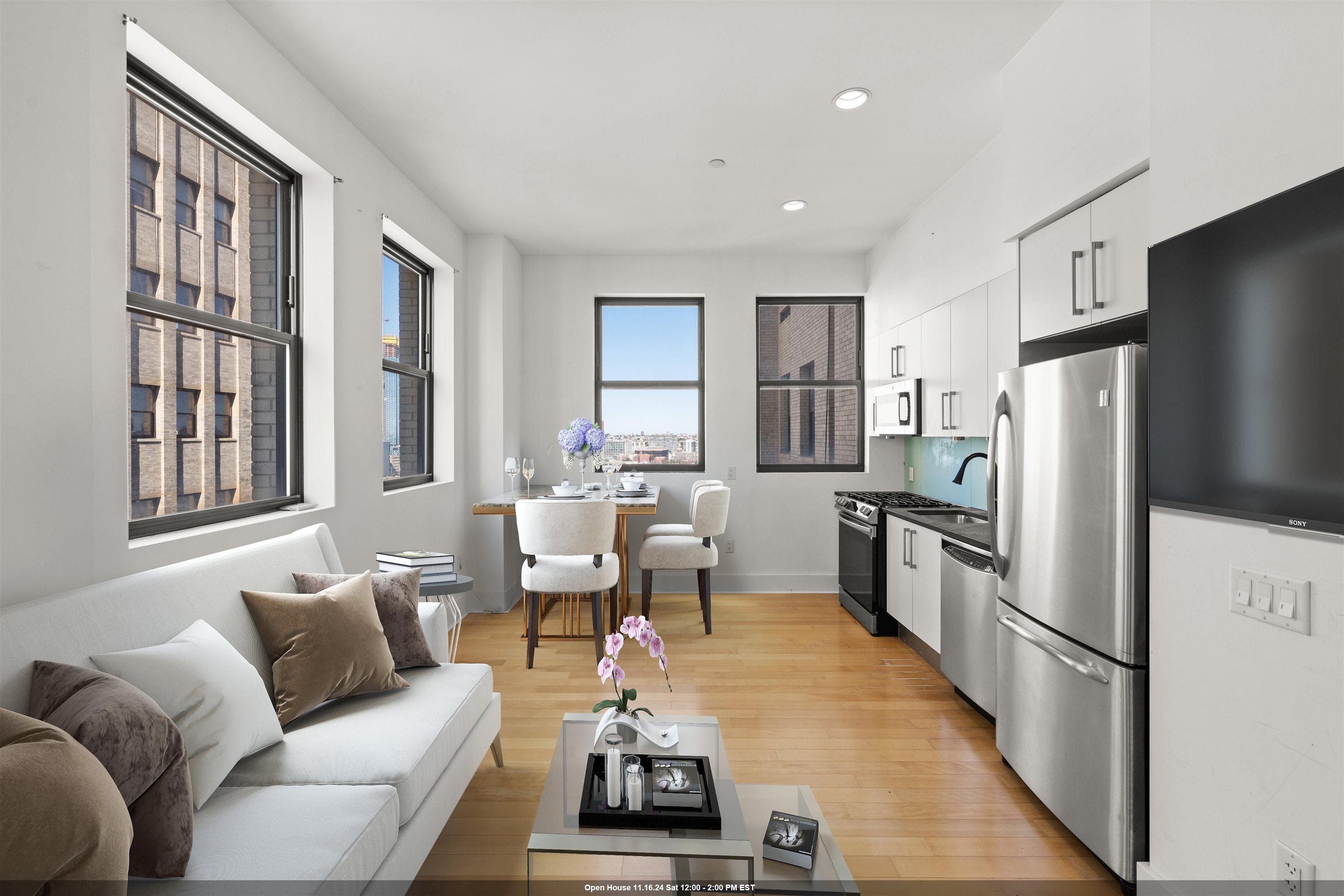 a living room with furniture a large window wooden floor and a refrigerator