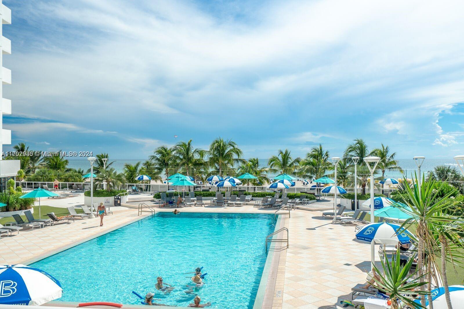 a view of swimming pool with outdoor seating and trees in the background