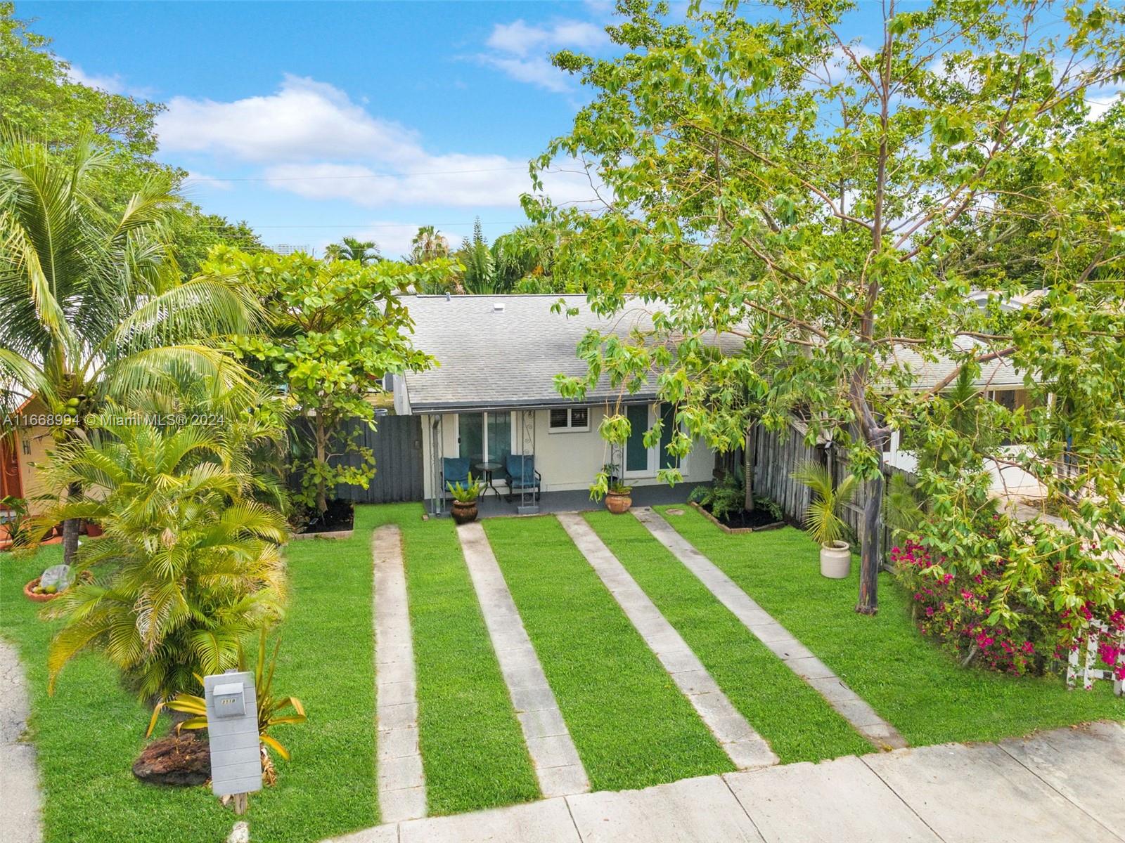 a view of a house with a big yard plants and large trees