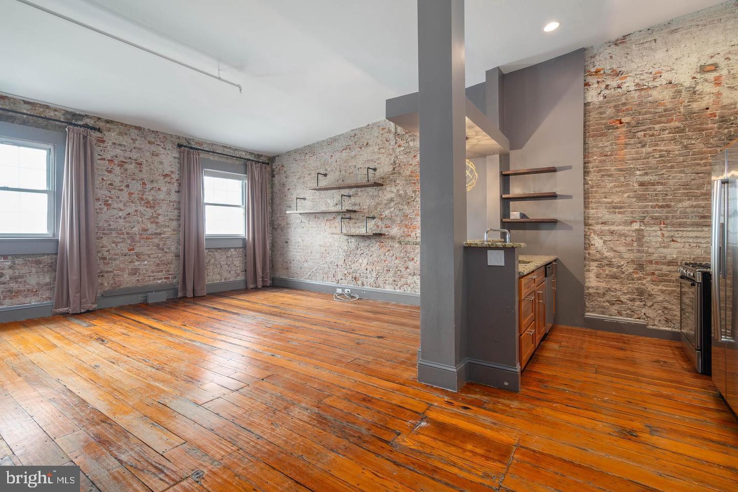 a view of empty room with wooden floor and windows