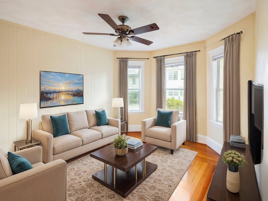 a living room with furniture ceiling fan and a window