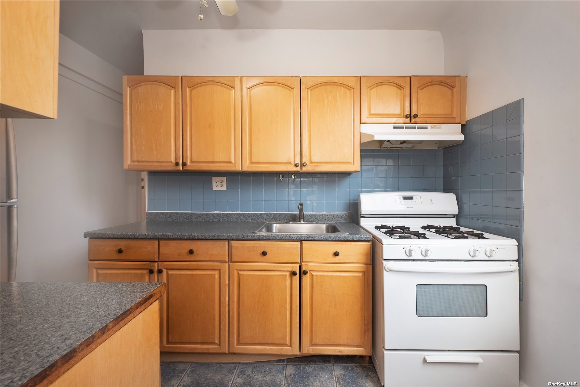 a kitchen with granite countertop a stove a sink and dishwasher with cabinets