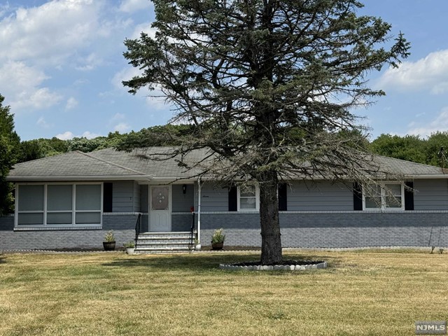 a front view of a house with a large tree