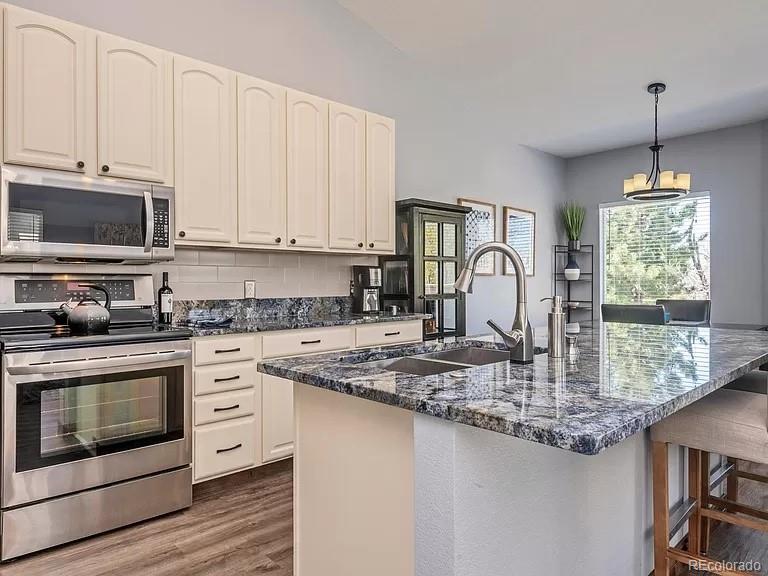 a kitchen with stainless steel appliances granite countertop a stove a sink and a microwave