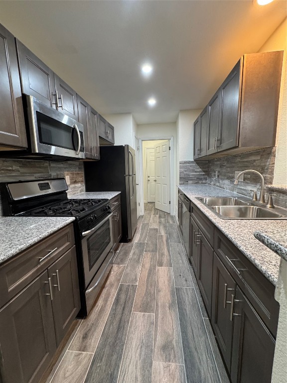 a kitchen with stainless steel appliances granite countertop refrigerator a sink a stove top oven and wooden floors